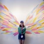 En deltagare som står fram för ett par vingar och ler.